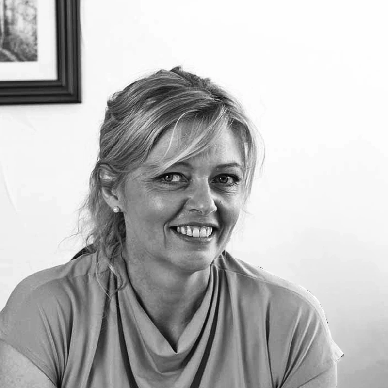Portrait en noir et blanc de Carole, experte foncier et immobilier, souriante en interieur